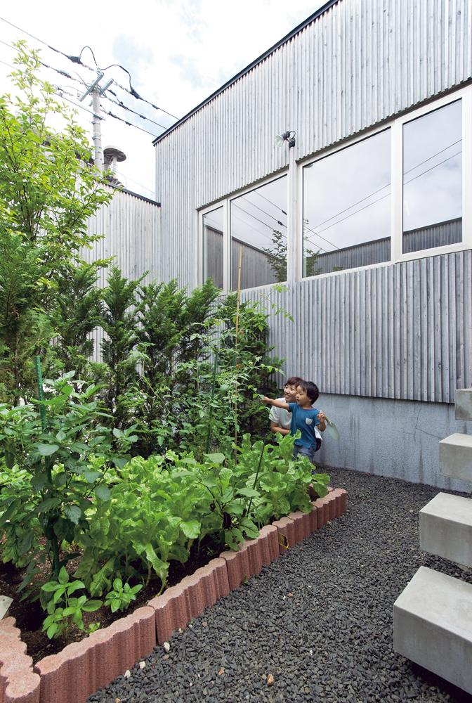 キッチンに面した庭で家庭菜園。穫れたてを食卓へ。このほか、ユーティリティに面した庭には物干しポールが備えられており、冬になると積もった雪で滑り台をつくり、お子さんたちのかっこうの遊び場になるそうだ