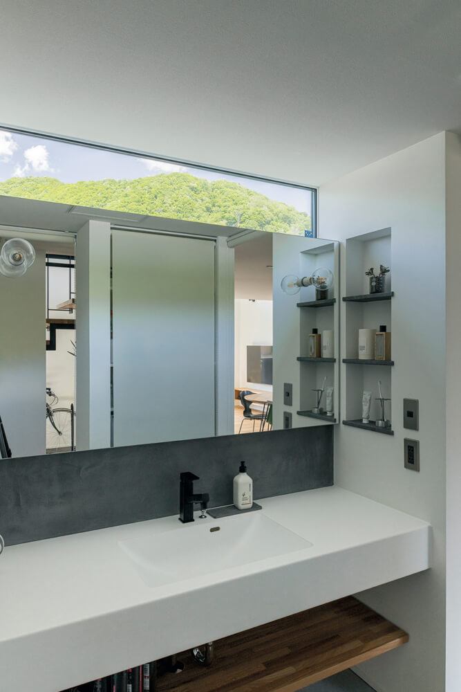 キッチンに隣接する独立型の洗面台は造作仕様。鏡の下はキッチンと同じモールテックスで仕上げ、統一感を演出